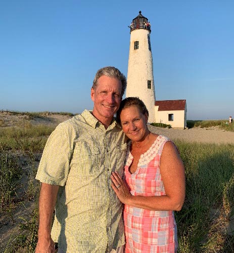 Chris Detmer and his wife with a lighthouse behind them